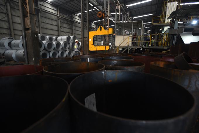 Pekerja mengawasi pengoperasian mesin pengangkut lembaran baja di pabrik Sunrise Steel, Mojokerto, Jawa Timur, Kamis (18/2).