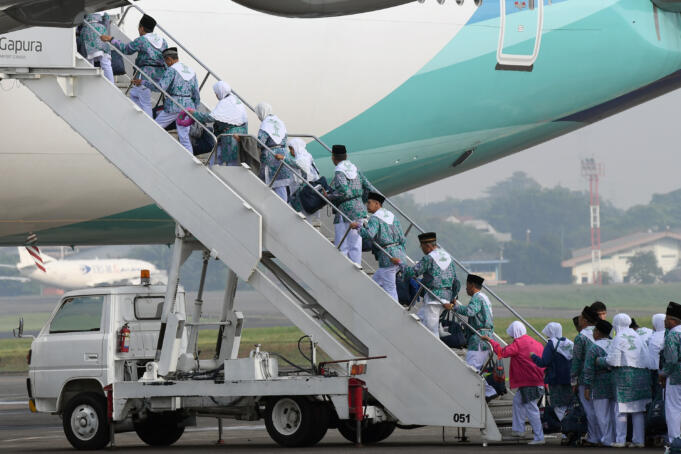 Jamaah calon haji menaiki tangga pesawat Garuda Indonesia saat pemberangkatan kloter pertama Embarkasi Jakarta Pondok Gede, Halim Perdanakusuma, Jakarta, Selasa (9/8).
