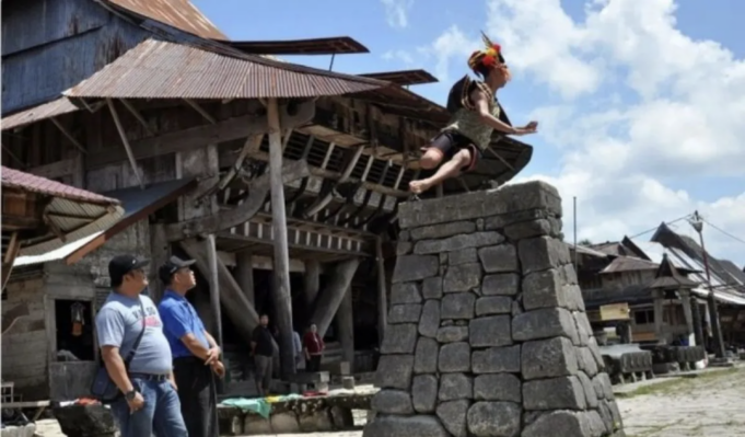 Screenshot 2026-04-02 at 9.58.22 AM Pelompat batu melompati tumpukan batu setinggi 2,1 meter untuk difoto bersama para turis mengunjungi desa cagar budaya nasional Bawomataluo, Kecamatan Fanayama, Kabupaten Nias Selatan, Sumatera Utara, Sabtu (9/3/2019). Hombo (lompat) batu dalam bahasa suku Nias merupakan salah satu ciri khas budaya dari Nias Selatan yang berasal dari tradisi latihan perang pada masa kerajaan. ANTARA FOTO/Septianda Perdana